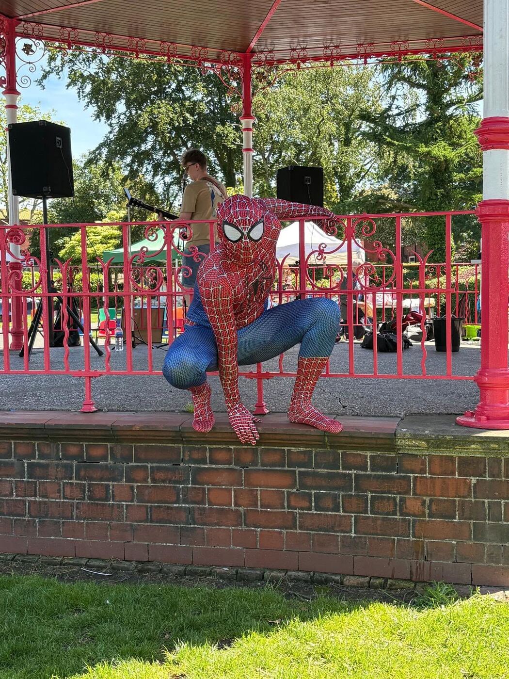 Spider-Man crouching on a railing at an outdoor community event