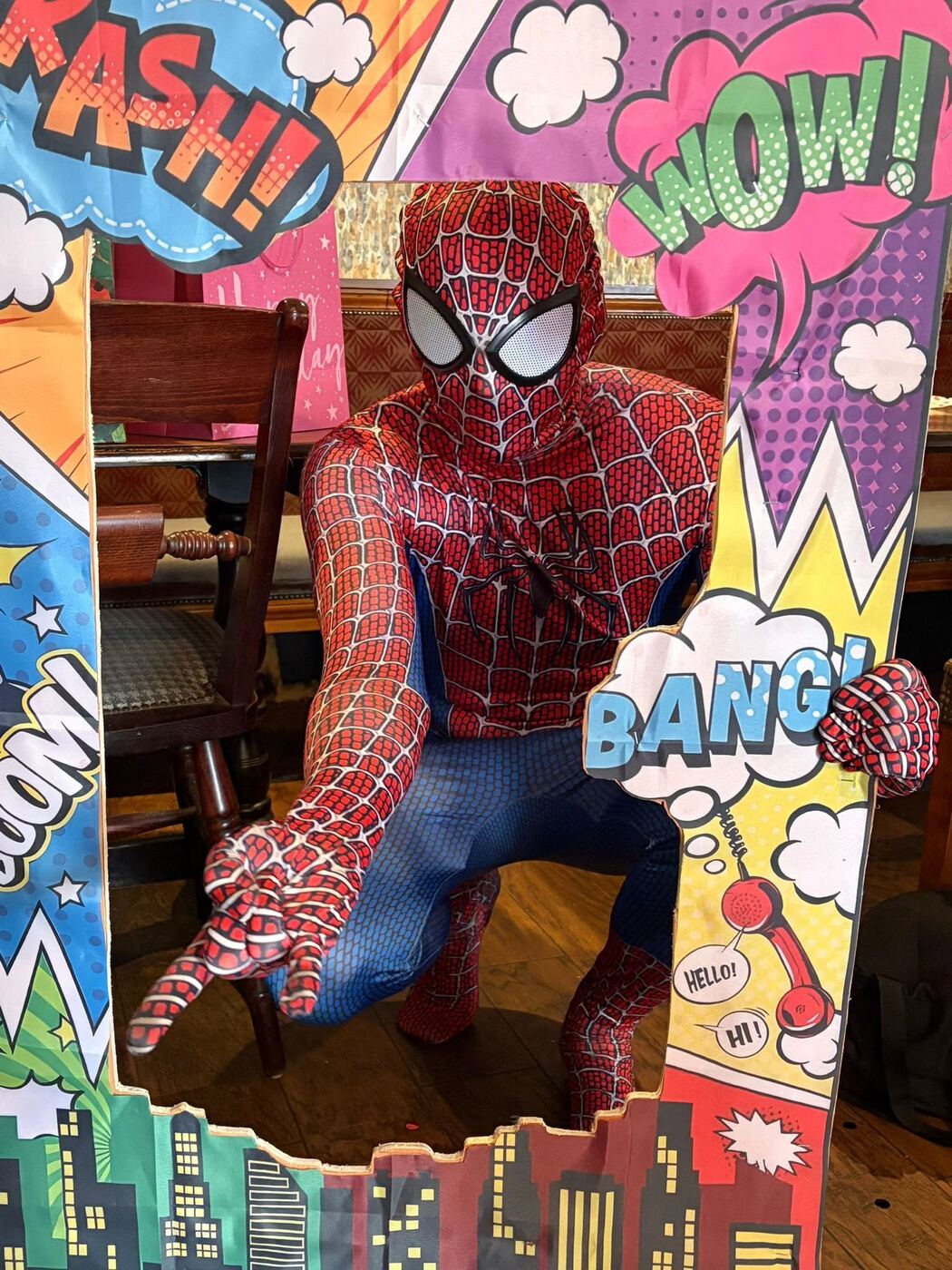 Spider-Man posing in a comic-book themed photo frame at a party